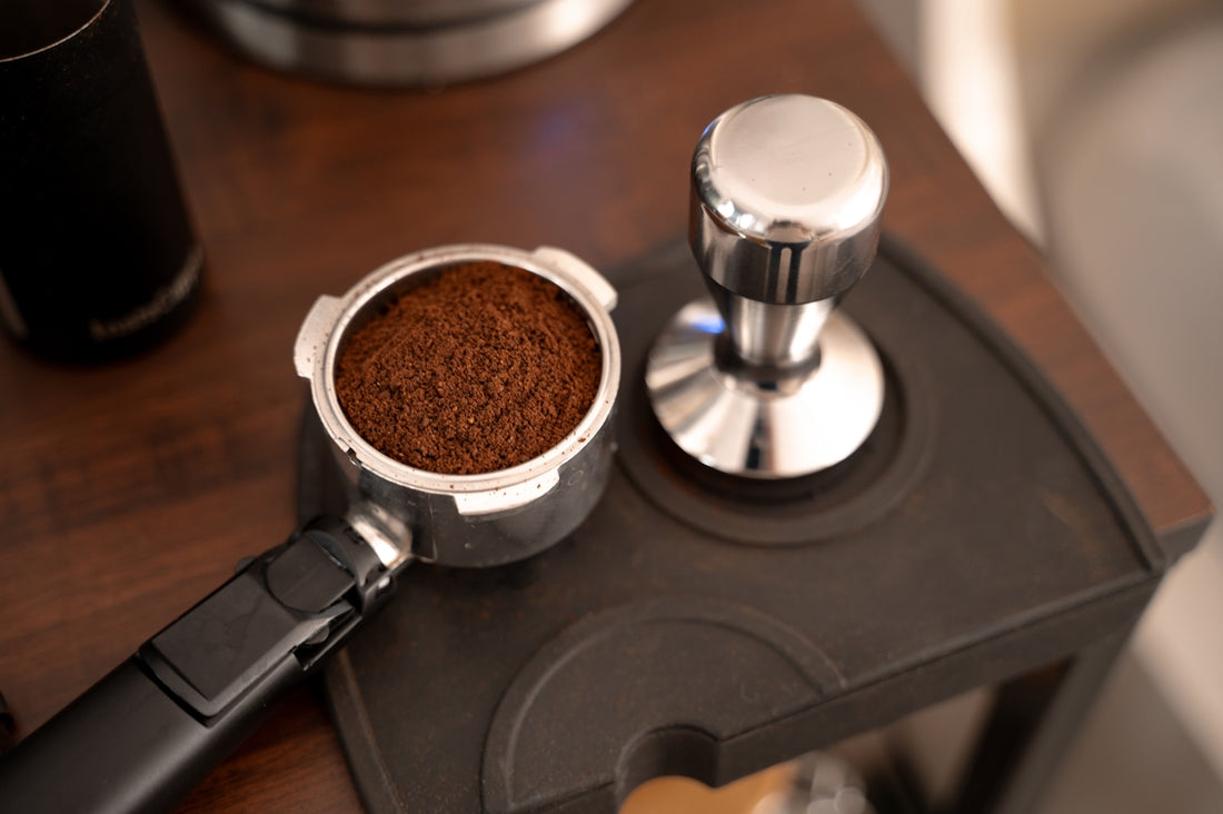 A wooden table topped with a grinder and a cup of coffee