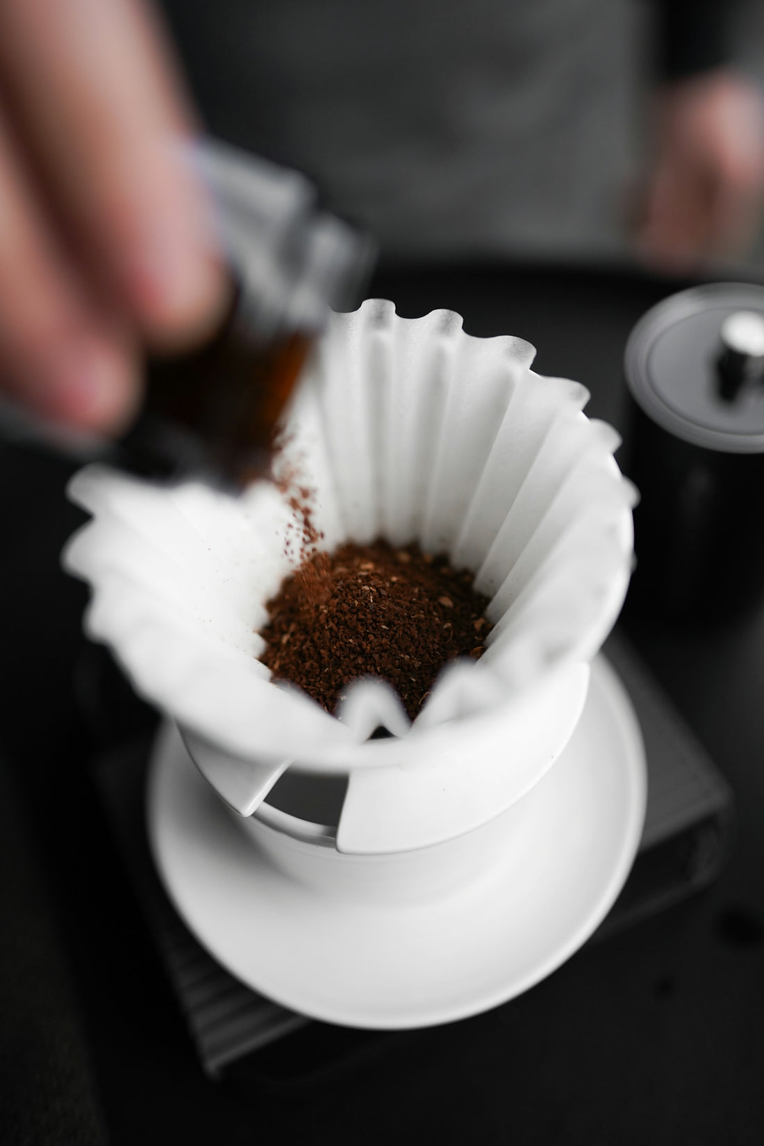 A person pours coffee into a white cup