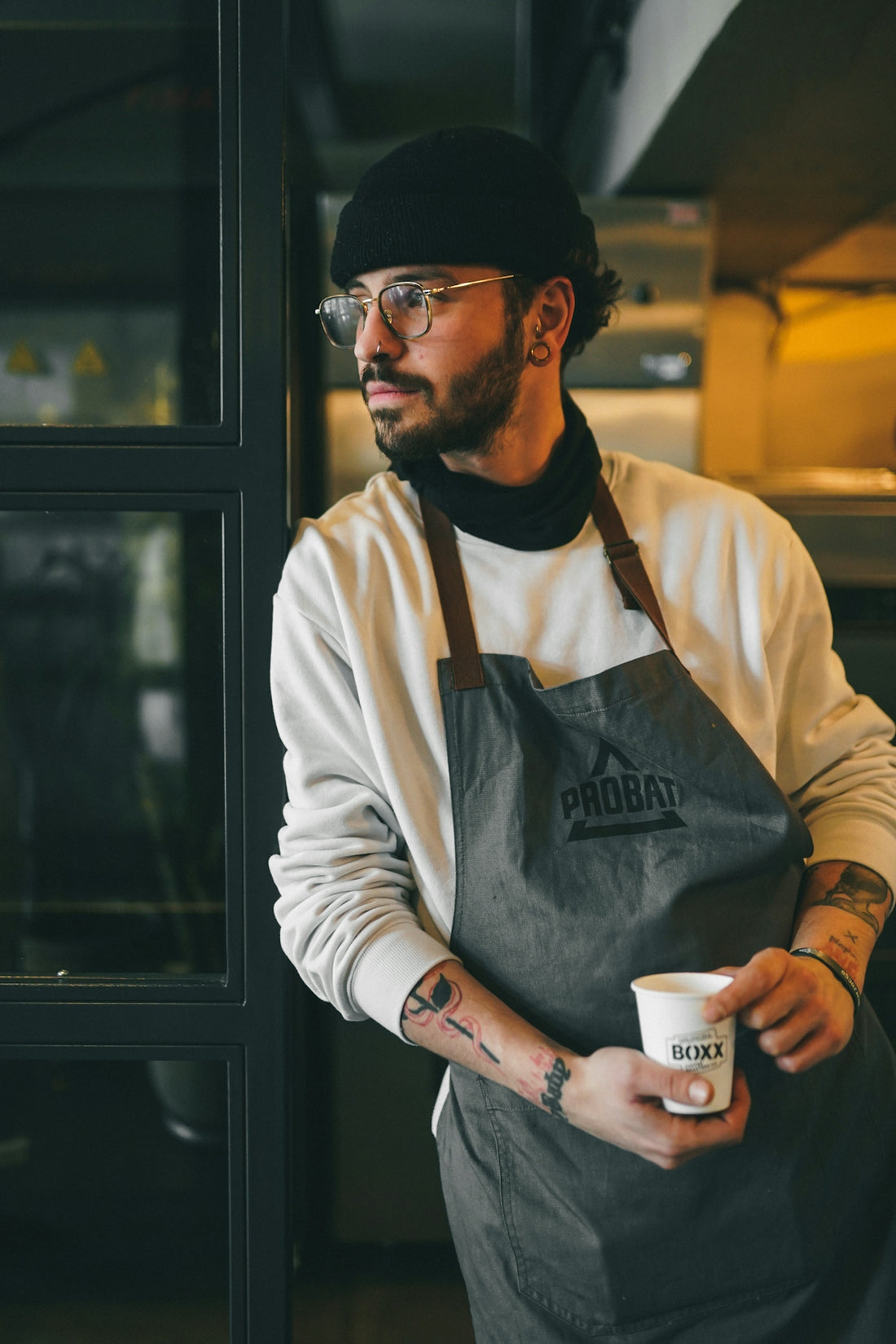 A man in an apron holding a cup of coffee