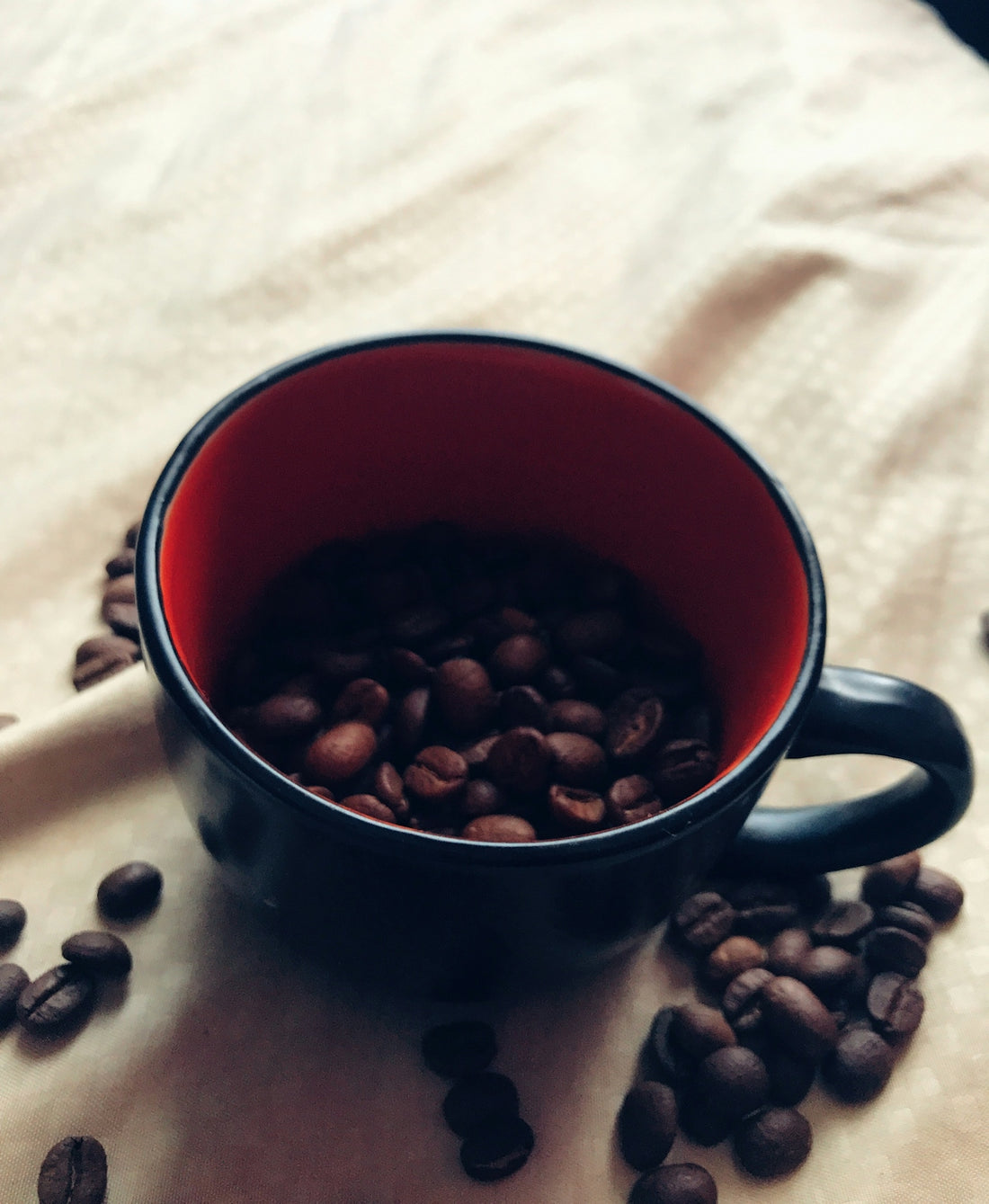 red ceramic mug on white textile