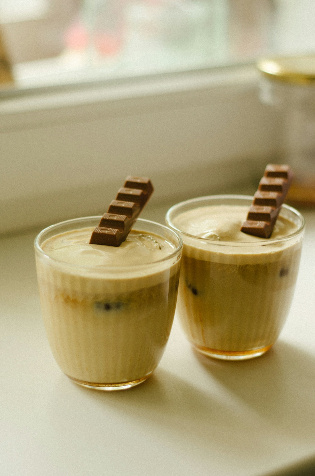 two glasses of dessert sitting on a window sill