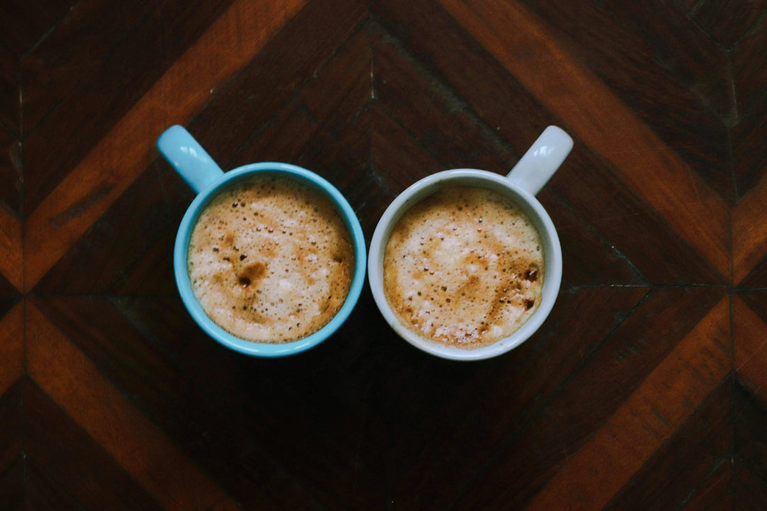 two cups of coffee sitting on top of a wooden table