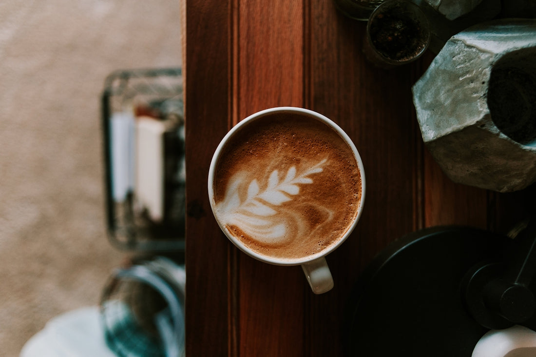 a cup of coffee on a table next to a blender