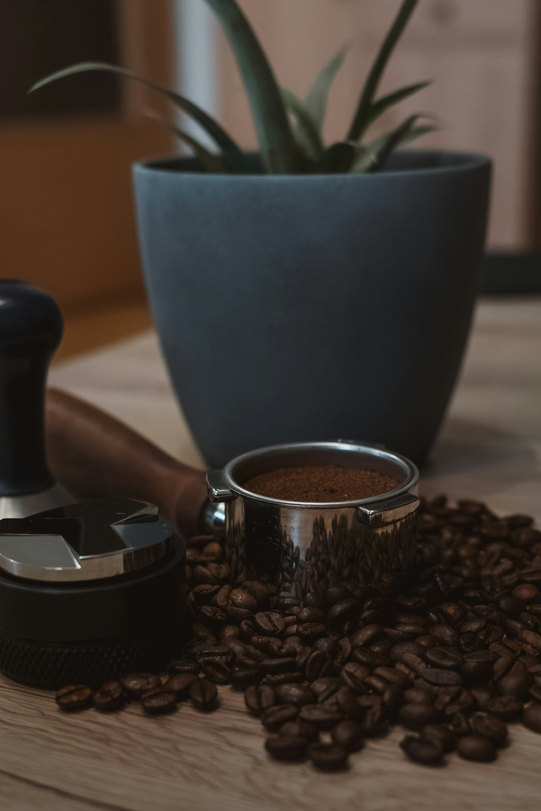 A cup of coffee next to a grinder and coffee beans