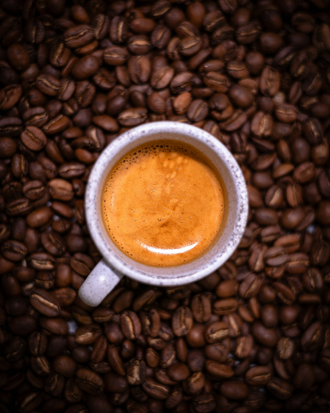 Espresso sits atop a bed of roasted coffee beans